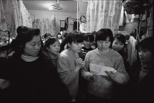 Female workers from a foreign toy factory in Huangtian of Baoan District read a letter from home in her dormitory. [Photographed in 1992] 